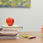 Photo of schoolbooks and apple on table top